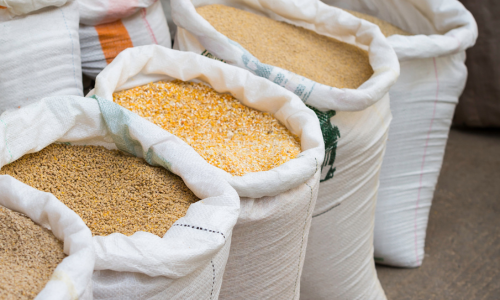 Open feed bags lined up on a concrete floor, displaying the contents inside.